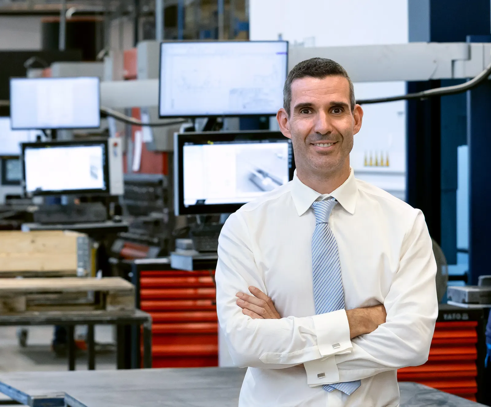Managing Director László Virág, arms folded, in front of the engineering CAD workstations